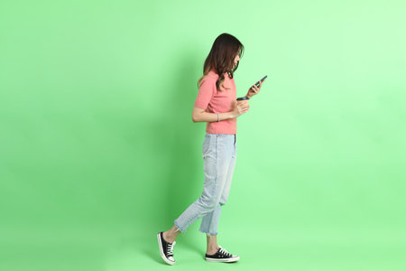 The young adult Asian woman with casual clothes with jeans standing on the green background.の写真素材
