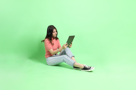 The young adult Asian woman with casual clothes with jeans standing on the green background.の写真素材