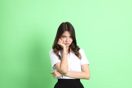 The young school girl with uniform standing on the green background.の写真素材