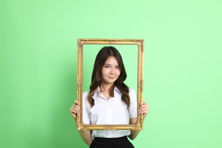 The young school girl with uniform standing on the green background.の写真素材