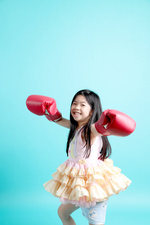 The cute Asian girl with boxing gloves standing on the green background.の写真素材
