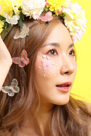 The Asian beautiful woman with flower sitting in the yellow background.の写真素材