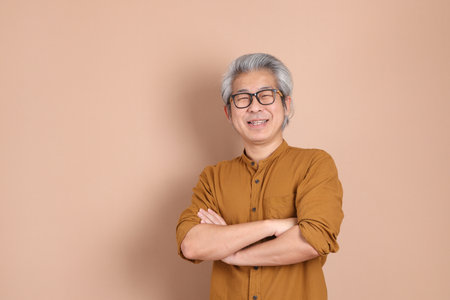 The 40s adult Asian man with yellow shirt standing on the brown background.の写真素材