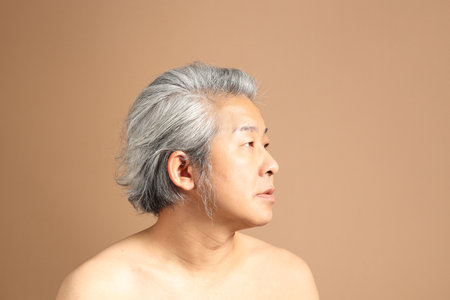 The 40s adult Asian man portrait with brown background showing clean face skinの写真素材