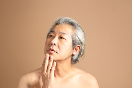 The 40s adult Asian man portrait with brown background showing clean face skinの写真素材