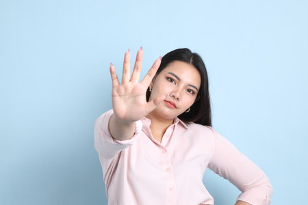 The Asian woman in casual clothes standing on the blue background.の写真素材