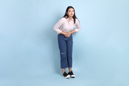 The Asian woman in casual clothes standing on the blue background.の写真素材