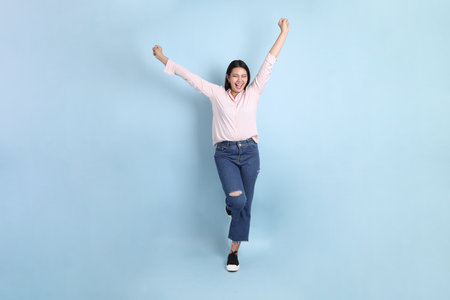 The Asian woman in casual clothes standing on the blue background.の写真素材