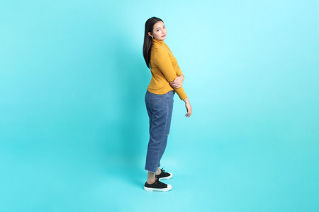 The Asian woman in casual clothes standing on the green background.の写真素材