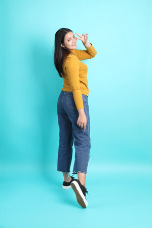 The Asian woman in casual clothes standing on the green background.の写真素材