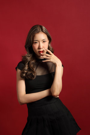 The Asian woman with black color dressed standing on the red background.の写真素材