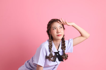 The Asian girl in Thai student uniform standing on the pink background.の写真素材