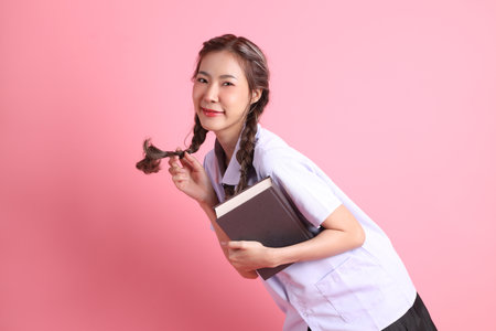The Asian girl in Thai student uniform standing on the pink background.の写真素材