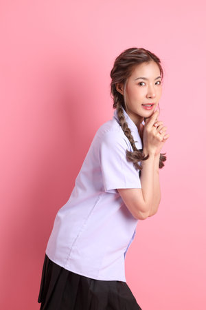 The Asian girl in Thai student uniform standing on the pink background.の写真素材