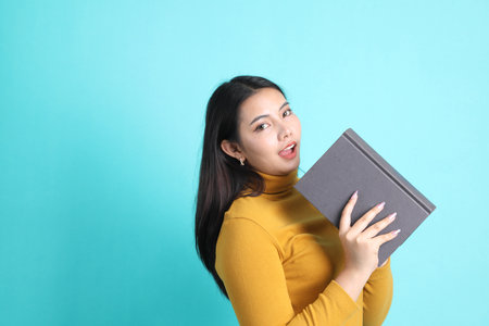 The Asian woman in casual clothes standing on the green background.の写真素材
