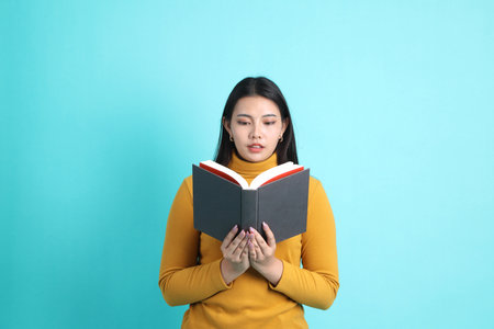 The Asian woman in casual clothes standing on the green background.の写真素材