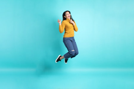 The Asian woman in casual clothes standing on the green background.の写真素材