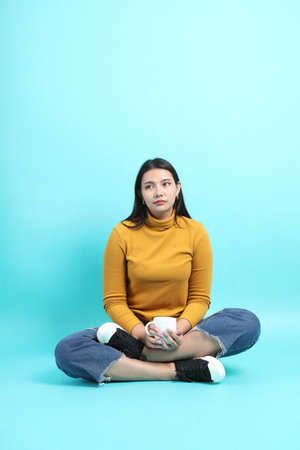 The Asian woman in casual clothes sitting on the green background.の写真素材