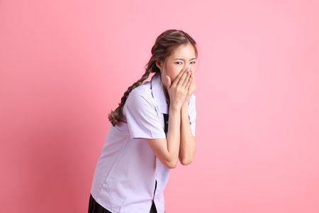 The Asian girl in Thai student uniform standing on the pink background.の写真素材