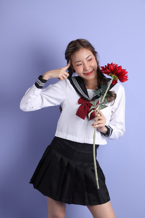 The Asian girl in Japanese student uniform standing on the purple background.の写真素材