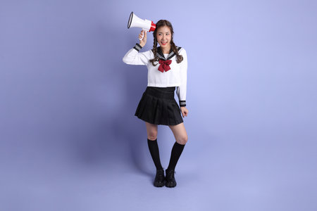 The Asian girl in Japanese student uniform standing on the purple background.の写真素材