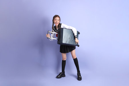 The Asian girl in Japanese student uniform standing on the purple background.の写真素材