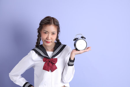 The Asian girl in Japanese student uniform standing on the purple background.の写真素材