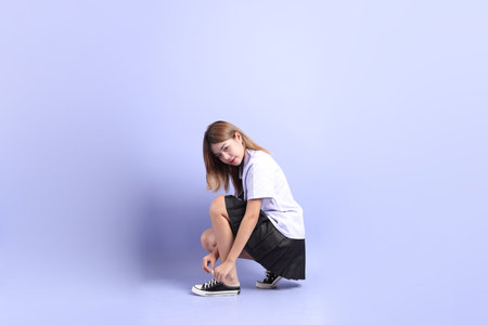 The Asian girl in Thai student uniform sitting on th floor on the purple background.の写真素材