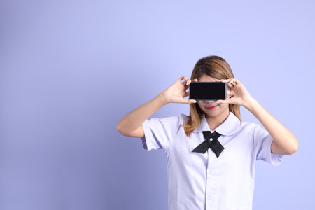 The Asian girl in Thai student uniform standing on the purple background.
