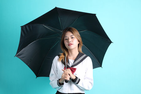 The Asian girl in Japanese student uniform standing on the green background.
