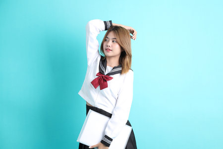 The Asian girl in Japanese student uniform standing on the green background.の写真素材