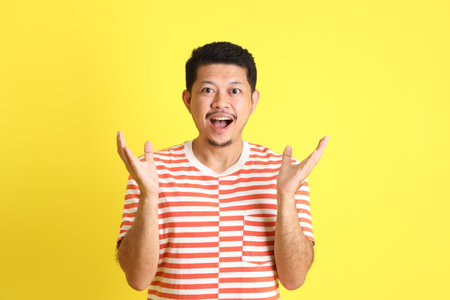 The adult Asian man in casual clothes standing on the yellow background.の写真素材