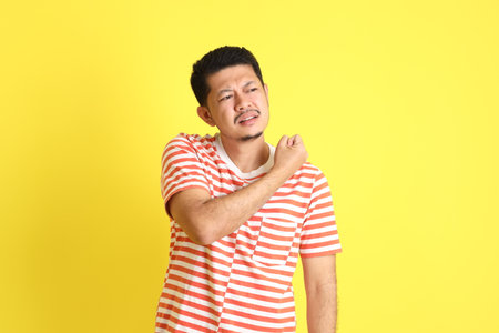 The adult Asian man in casual clothes standing on the yellow background.の写真素材