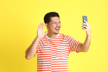 The adult Asian man in casual clothes standing on the yellow background.の写真素材