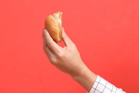 The Asian man hand holding hamburger on the orange background.の写真素材