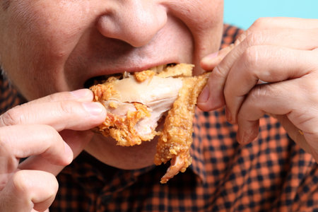 The Asian man eating deep fried chicken on the green background.の写真素材