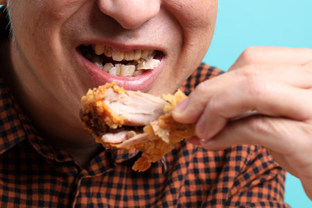 The Asian man eating deep fried chicken on the green background.の写真素材