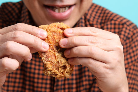 The Asian man eating deep fried chicken on the green background.の写真素材