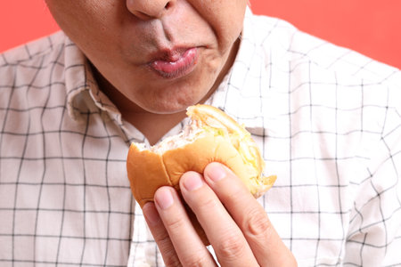 The Asian man eating hamburger on the orange background.の写真素材