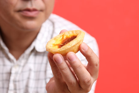 The Asian man hand holding egg tart in the orange background.の写真素材