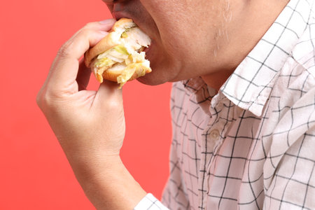 The Asian man eating hamburger on the orange background.の写真素材