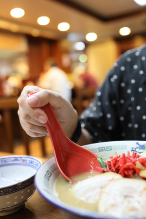 The Asian woman eating ramen in the restaurant.の写真素材