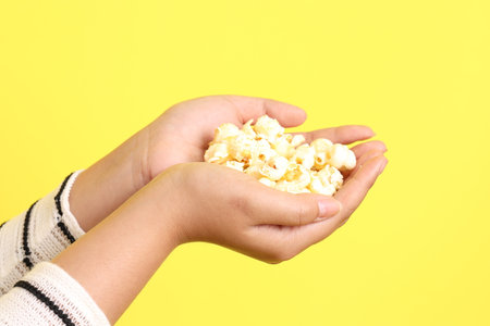The Asian woman holding popcorn in the hand on the yellow background.の写真素材