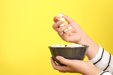 The Asian woman holding popcorn in the hand on the yellow background.の写真素材