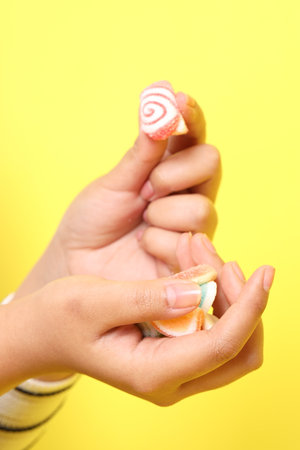 The Asian woman holding jelly in the hand on the yellow background.の写真素材