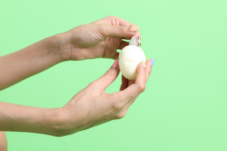 The Asian woman holding egg in the hand on the green background.の写真素材