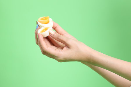 The Asian woman holding egg in the hand on the green background.の写真素材