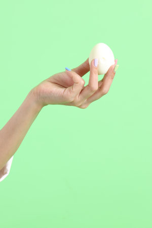 The Asian woman holding egg in the hand on the green background.の写真素材