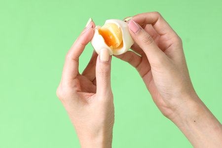 The Asian woman holding egg in the hand on the green background.の写真素材