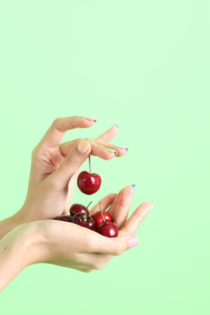 The Asian woman holding berry fruit in the hand on the yellow background.の写真素材